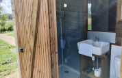 Bagno moderno in una cabina di legno al Domaine des Feuilles, Francia, con lavandino, doccia e WC.