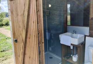 Modern badkamer in een houten cabine bij Domaine des Feuilles, Frankrijk, met wastafel en douche.