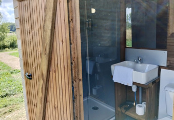 Modernes Badezimmer in einer Holzhütte bei Domaine des Feuilles, mit Waschbecken, Toilette und Dusche.