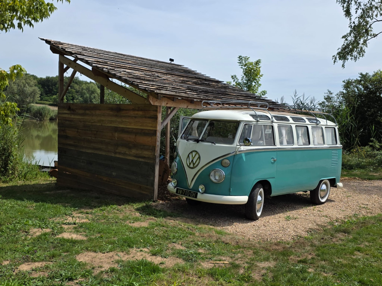 Foto van een vintage Volkswagen Combi busje naast een houten hut bij het meer bij Combi Harvey.