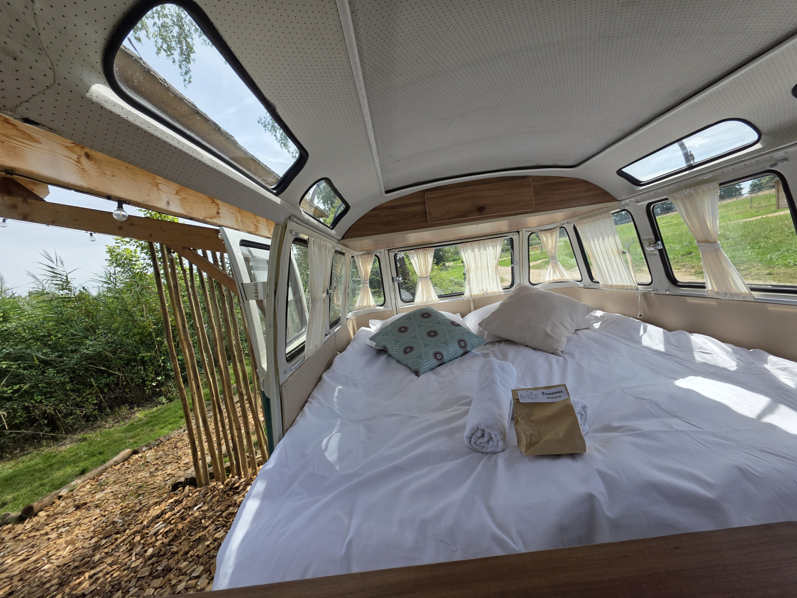 Interieurfoto van de Combi Harvey hut bij Domaine des Feuilles in Frankrijk met bed en open deur.