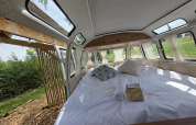 Interno della cabina Combi Harvey presso Domaine des Feuilles in Francia, con letto e porta aperta sul verde.