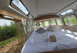 Interieur van Combi Harvey bij Domaine des Feuilles in Frankrijk, met een gezellig bed en open deur naar buiten.