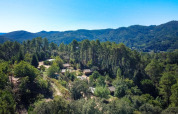 Luftfoto af Bivouac nature feriepark i Occitanie, Frankrig, omgivet af tæt skov og bjerge i baggrunden.