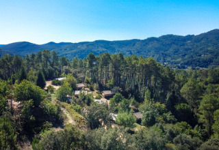 Aerial view of Bivouac nature holiday park in Occitanie, France, surrounded by dense forest and mountains.