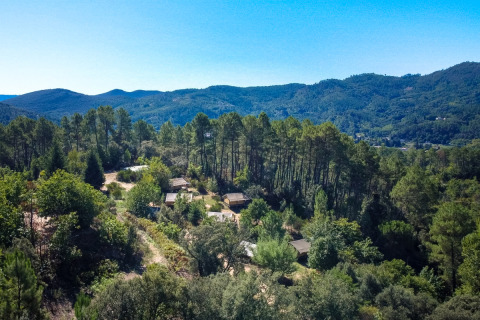 Vista aérea de Bivouac nature, un parque vacacional en Occitania, Francia, rodeado de bosques y montañas.
