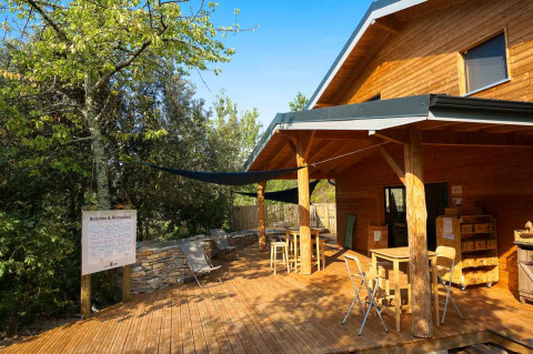 Terraza de madera junto a cabaña en Bivouac nature, un parque de vacaciones en Occitania, Francia, con sillas.
