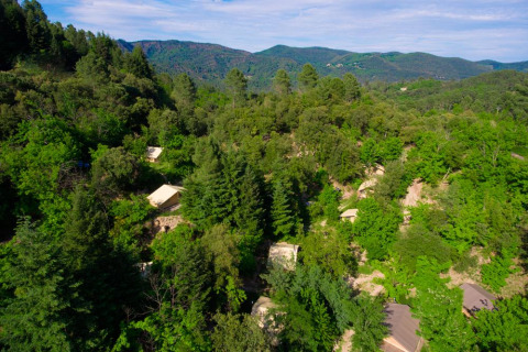 Vista aerea del parco vacanze Bivouac Nature in Occitania, Francia, immerso tra colline e foreste verdi.