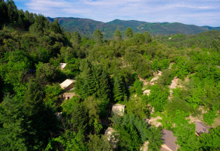 Luftfoto af Bivouac Nature feriepark i Occitanie, Frankrig, omgivet af frodig grøn skov og bakker.