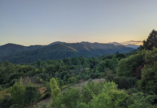 Panorama di verdi foreste e colline al tramonto dal parco vacanze Bivouac nature in Occitanie, Francia.