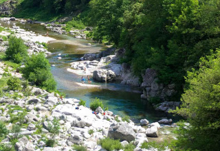 River with rocks and lush trees near Saint Jean du Gard, Occitanie, France, under summer sunlight.