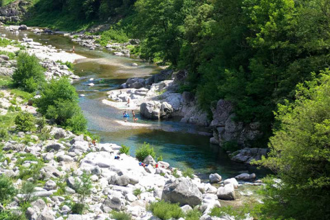 River with rocks and lush trees near Saint Jean du Gard, Occitanie, France, under summer sunlight.