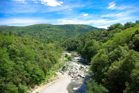 Landschaft mit grünem Wald, Fluss und Hügeln im Ferienpark Bivouac Nature in Okzitanien, Frankreich.