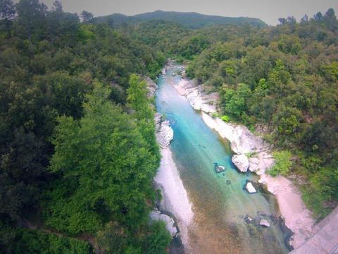 Vista aerea del fiume e della foresta al parco vacanze Bivouac nature in Occitania, Francia, circondato da colline.