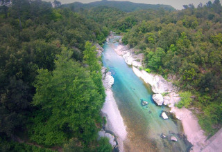 Luchtfoto van rivier en bos bij Bivouac nature vakantiepark in Occitanië, Frankrijk, omgeven door heuvels.