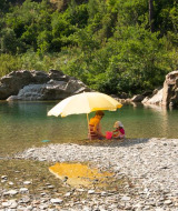 Twee mensen zitten onder een gele parasol bij een rivier in de buurt van Saint Jean du Gard, Occitanie, Frankrijk.