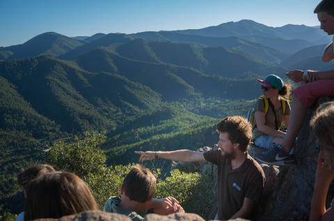 Un gruppo di persone ammira il panorama montano a Bivouac nature, un parco vacanze in Occitania, Francia.