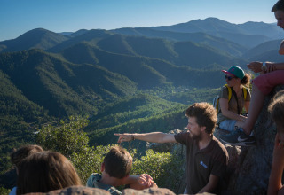 A group of people enjoy a scenic mountain view at Bivouac nature, a holiday park in Occitanie, France.