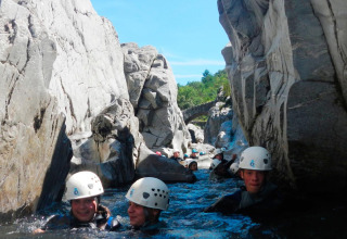 Groupe avec casques faisant du canyoning dans les gorges rocheuses de Bivouac nature, Occitanie, France.