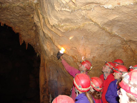 Gruppe mit roten Helmen erkundet eine Tropfsteinhöhle im Bivouac nature Ferienpark, Occitanie, Frankreich.