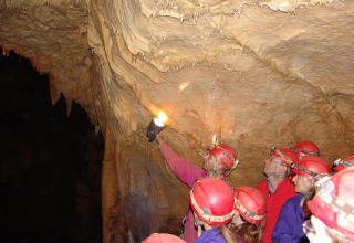 Groep met rode helmen verkent een grot in het Bivouac nature vakantiepark in Occitanië, Frankrijk.