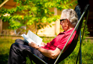 Älterer Mann liest entspannt ein Buch im Liegestuhl bei Bivouac nature, Occitanie, Frankreich.