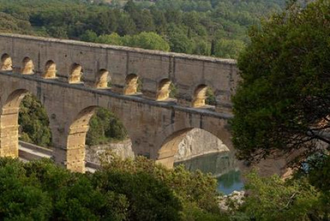 Uitzicht op het historische Pont du Gard-aquaduct tussen bomen bij Bivouac nature, Occitanië, Frankrijk.