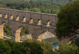 Uitzicht op het historische Pont du Gard-aquaduct tussen bomen bij Bivouac nature, Occitanië, Frankrijk.