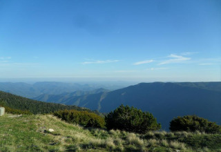 Udsigt over bjergene fra Bivouac nature feriepark i Occitanie, Frankrig, under en klar blå himmel.