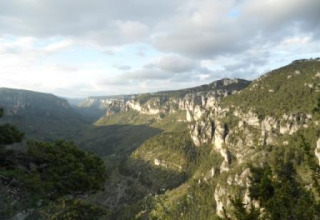 Vista panorámica de montañas rocosas y valle verde en Bivouac nature, parque vacacional en Occitanie, Francia.