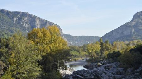 Naturpanorama im Ferienpark Bivouac nature in Occitanie, Frankreich, mit Bergen, Bäumen und Fluss.