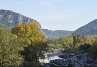 Naturpanorama im Ferienpark Bivouac nature in Occitanie, Frankreich, mit Bergen, Bäumen und Fluss.