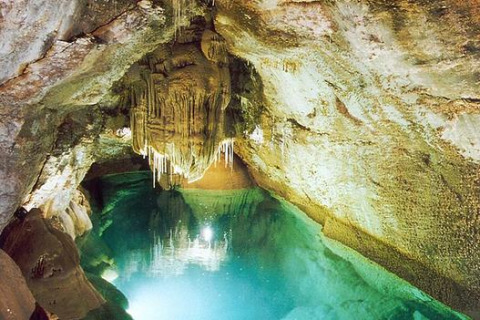 Underground cave med klart blåt vand og drypstensformationer, set i Bivouac nature feriepark i Occitanie, Frankrig.