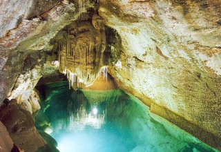 Grotta sotterranea con acqua limpida e stalattiti, fotografata al parco vacanze Bivouac nature in Occitanie, Francia.