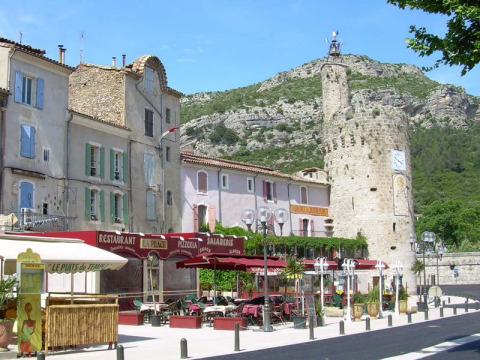 Caratteristica strada di Saint Jean du Gard, Occitania, Francia, con caffè, case pastello e torre storica.