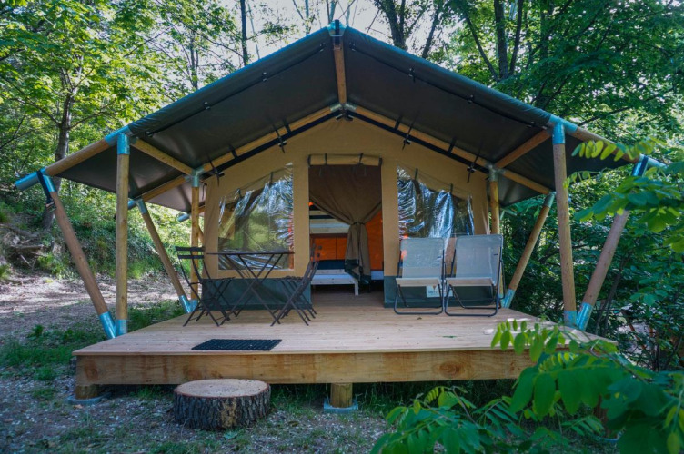 Baroudeur safaritent met houten terras, tuinmeubilair en een groene bosrijke omgeving.