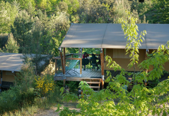 Tenda safari Baroudeur al Bivouac nature in Francia, immersa tra alberi e rigogliosa vegetazione.
