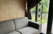 Graues Sofa in einer modernen Lodge mit Blick ins Grüne, aufgenommen bei Solo Retreat in Reestervallei, Niederlande.