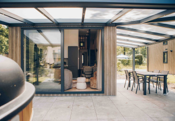 Outdoor terrace at a modern lodge featuring large windows, covered dining area, and a green view.