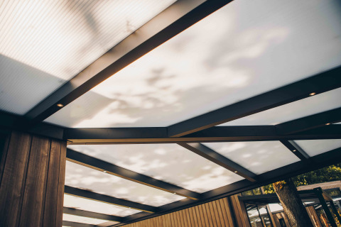 Modern patio roof with black beams and wood siding at Reeëndal Lodge, Veluwepark de Bosgraaf, Netherlands.