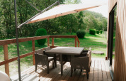 Veranda in legno con tavolo, sedie e ombrellone presso Eco Lodge MOBIWOOD, Camping Floreal La Roche-en-Ardenne.