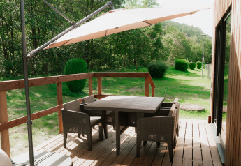 Wooden patio with outdoor dining furniture and umbrella at Eco Lodge MOBIWOOD, Camping Floreal La Roche-en-Ardenne.