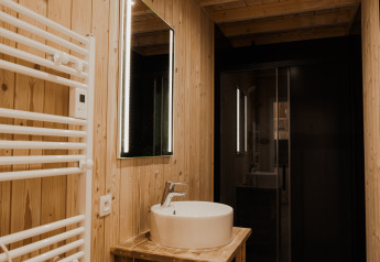 Modern bathroom with wooden walls, illuminated mirror, and round sink at Eco Lodge MOBIWOOD in Belgium.