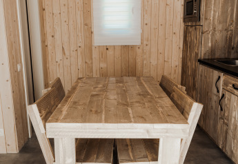 Tavolo da pranzo rustico in legno e panche nella cucina dell’Eco Lodge MOBIWOOD, Camping Floreal La Roche-en-Ardenne.
