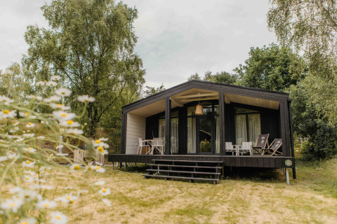 Foto van The Hills met Hottub lodge, gelegen in het groen met houten terras en buitenzitjes.