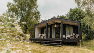 Foto van The Hills met Hottub lodge omringd door natuur, met terras en loungestoelen buiten.