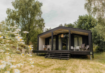 Foto van The Hills met Hottub lodge omringd door natuur, met terras en loungestoelen buiten.