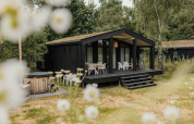 The Hills lodge met hottub bij Wilsumer Berge, Duitsland, te midden van natuur en bloemen op de voorgrond.