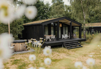 The Hills lodge met hottub bij Wilsumer Berge, Duitsland, te midden van natuur en bloemen op de voorgrond.