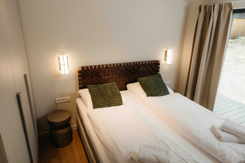 Moderne slaapkamer bij The Hills met Hottub, Wilsumer Berge, Duitsland, met twee bedden en groene kussens.